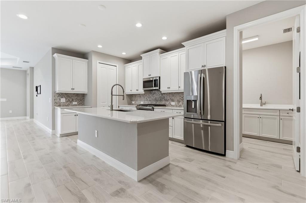 2118 Marquesa Circle Naples, FL 34112 - Photo 12 of 50 a kitchen with white cabinets and stainless steel appliances
