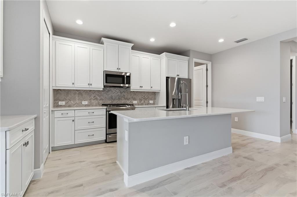 2118 Marquesa Circle Naples, FL 34112 - Photo 14 of 50 a kitchen with kitchen island granite countertop white cabinets and stainless steel appliances