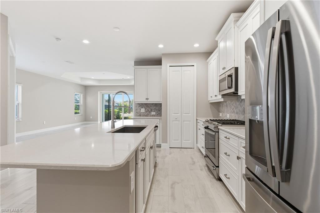 2118 Marquesa Circle Naples, FL 34112 - Photo 16 of 50 a kitchen with stainless steel appliances granite countertop a sink stove and refrigerator