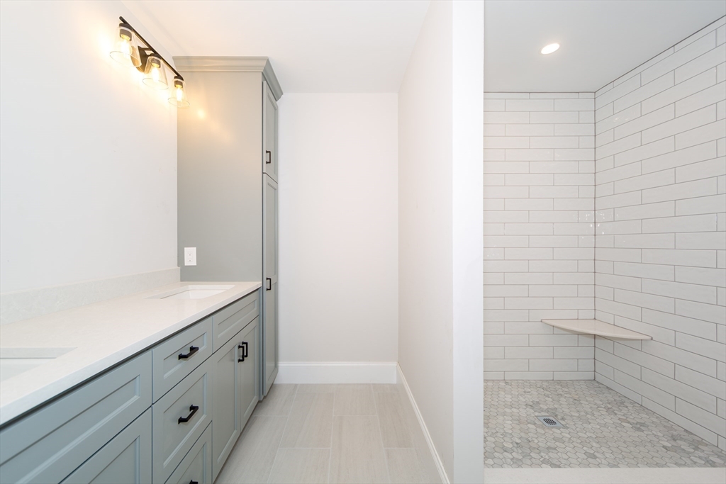 293 Bacon Street, Unit A Natick, MA 01760 - Photo 28 of 35 a bathroom with a granite countertop sink a toilet and shower