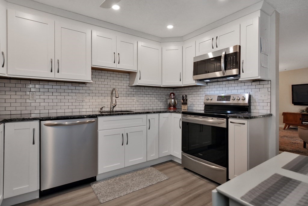 a kitchen with white cabinets and stainless steel appliances