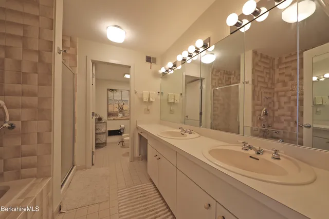 a spacious bathroom with a double vanity sink a large mirror and shower