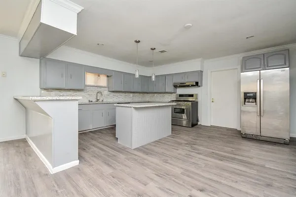 a kitchen with stainless steel appliances granite countertop a stove top oven a sink and white cabinets