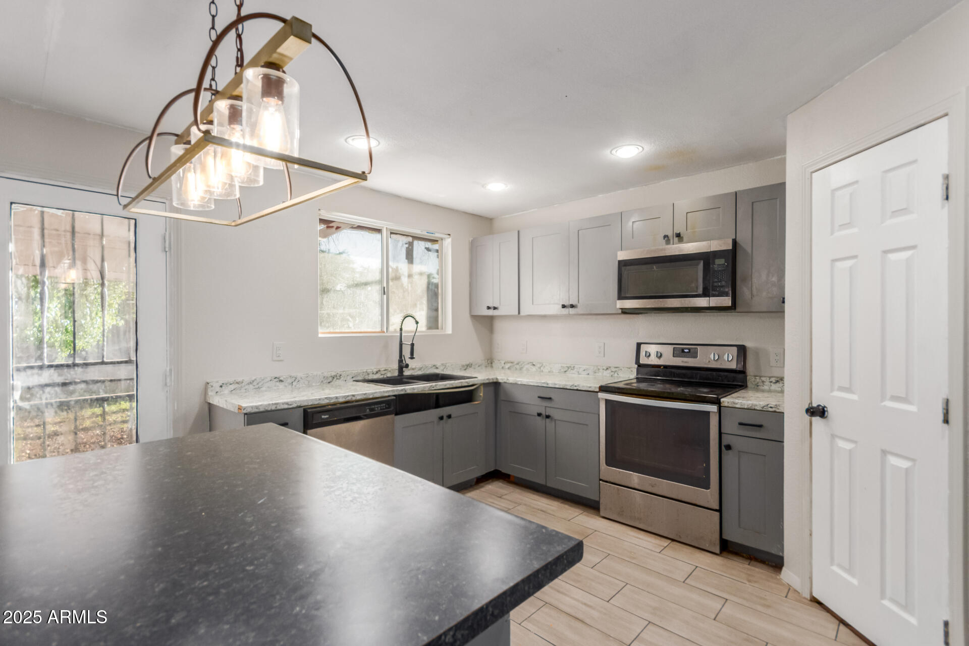4727 West Osborn Road Phoenix, AZ 85031 - Photo 7 of 22 a kitchen with stainless steel appliances granite countertop a stove a sink and a microwave
