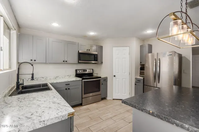 a kitchen with stainless steel appliances granite countertop a sink stove and refrigerator
