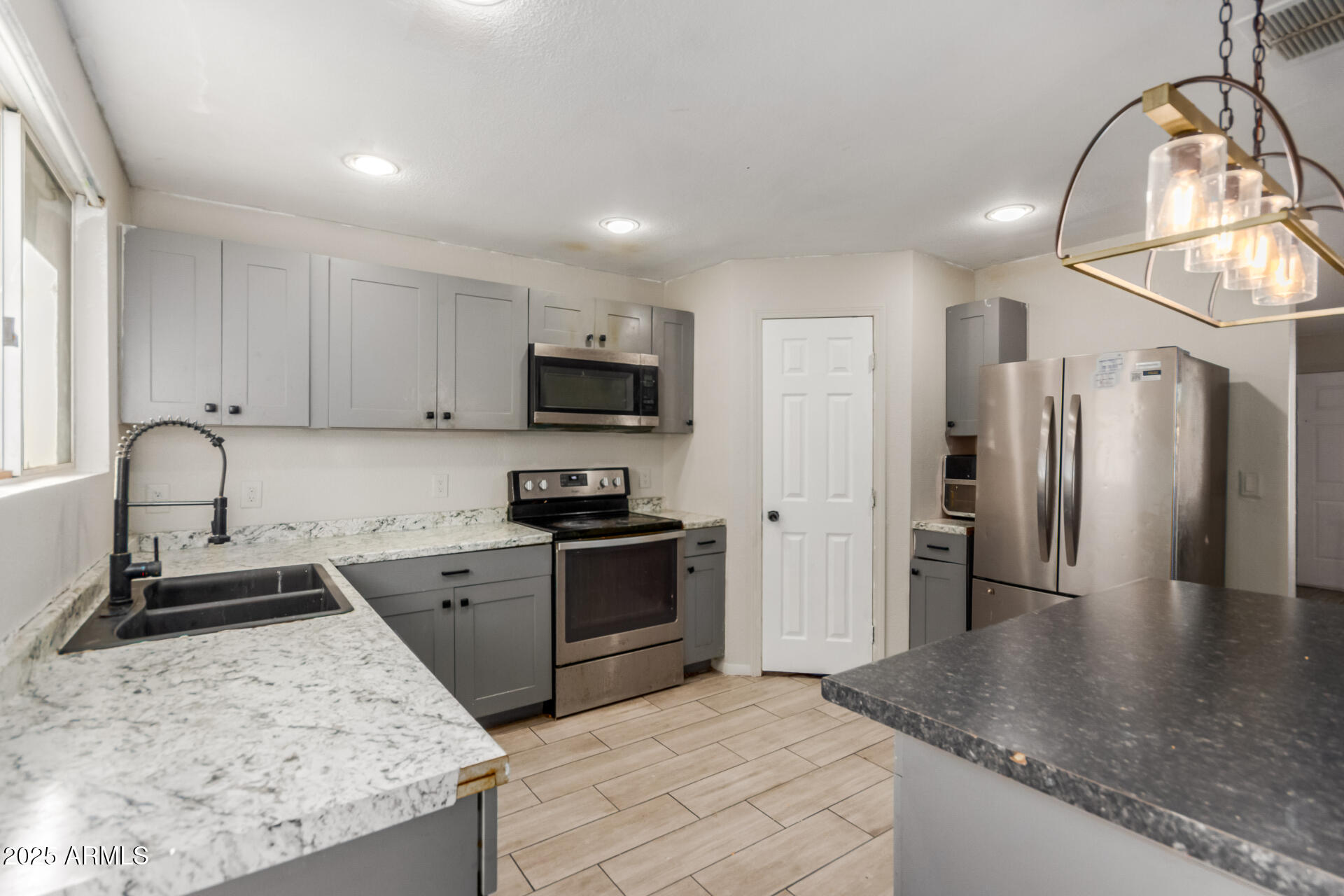 4727 West Osborn Road Phoenix, AZ 85031 - Photo 8 of 22 a kitchen with stainless steel appliances granite countertop a sink stove and refrigerator