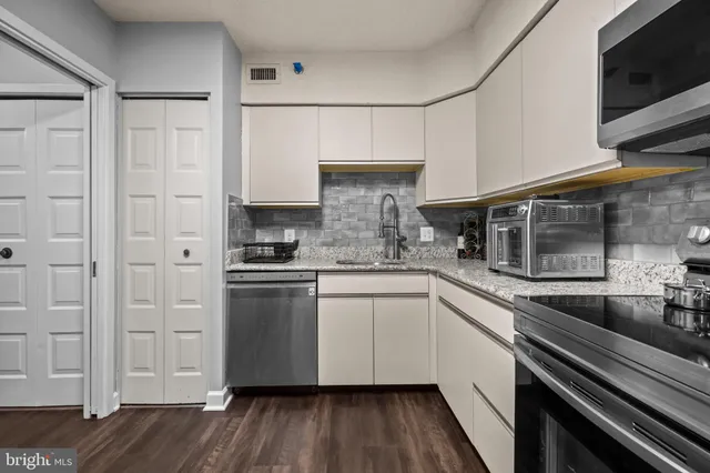 a kitchen with stainless steel appliances a stove a chimney a dining table and chairs