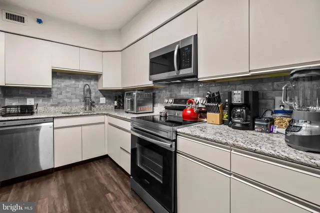 a kitchen with granite countertop white cabinets and stainless steel appliances