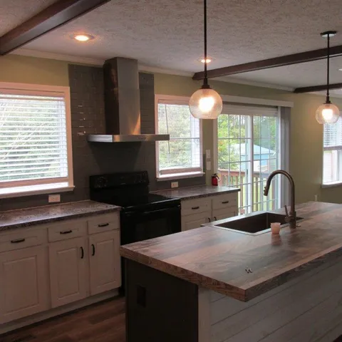 a kitchen with a kitchen island hardwood floor sink stove and granite counter top