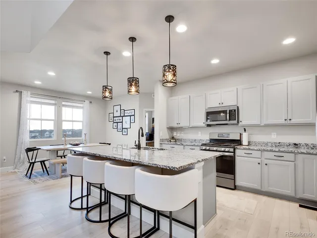 a kitchen with stainless steel appliances granite countertop a stove top oven a sink a stove a dining table and chairs