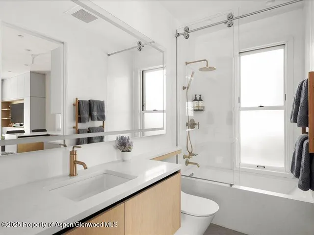 a bathroom with a granite countertop sink a toilet a mirror and shower