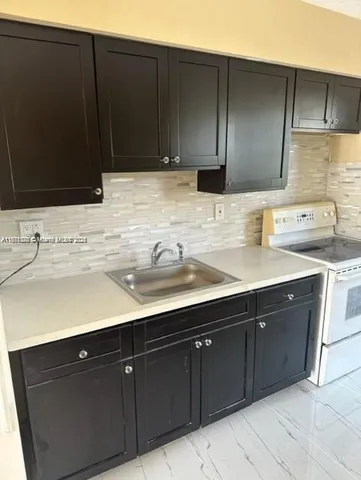 a sink with granite countertop cabinets and black appliances