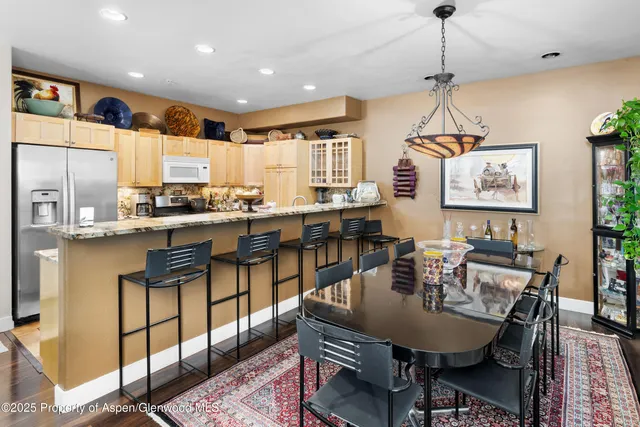 a dining room with stainless steel appliances granite countertop a dining table chairs with the kitchen view