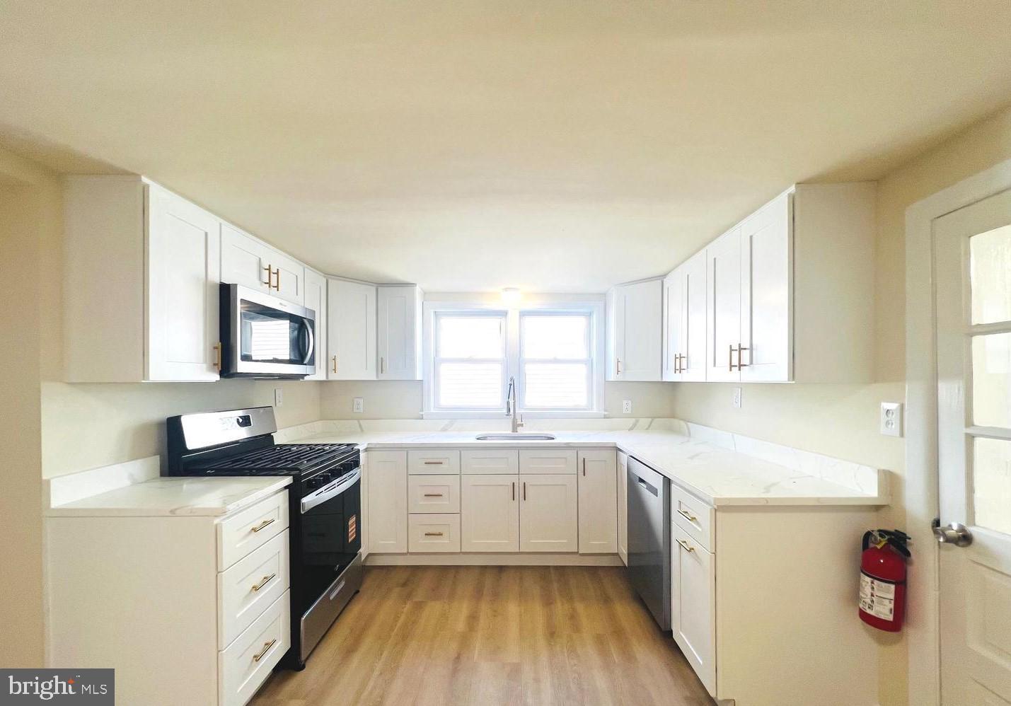 617 3rd Street Beverly, NJ 08010 - Photo 3 of 16 a kitchen with a sink dishwasher a stove and white cabinets with wooden floor
