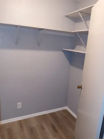 an empty room with wooden floor and hallway