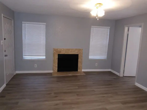 an empty room with windows cabinet and fireplace