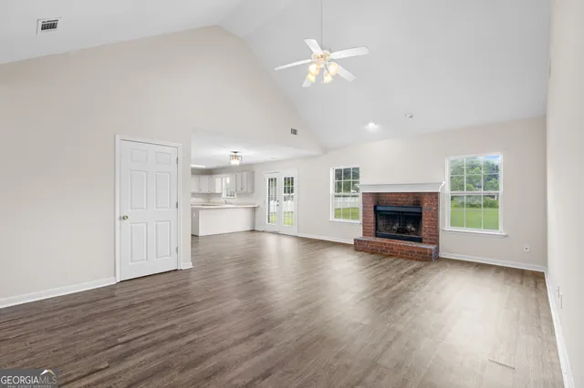 an empty room with wooden floor fireplace and windows
