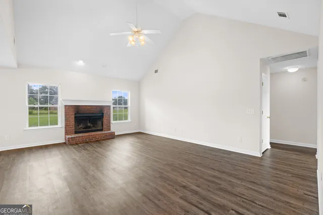 an empty room with wooden floor fireplace and windows