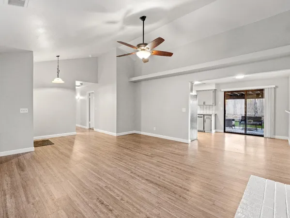 a view of an empty room with window and wooden floor