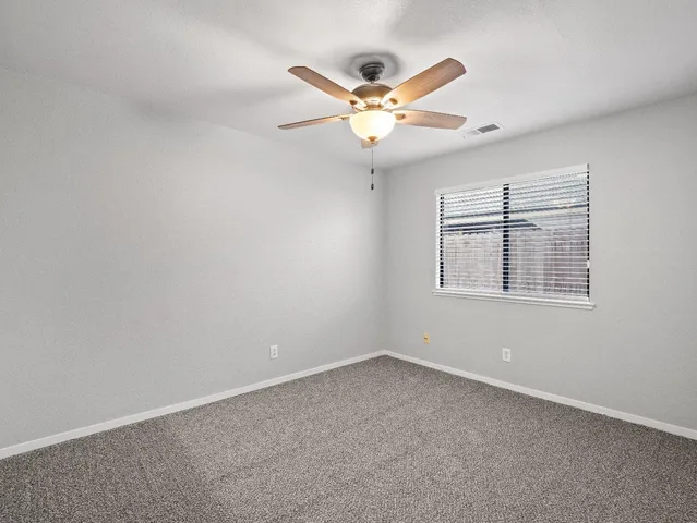 a view of an empty room and chandelier fan