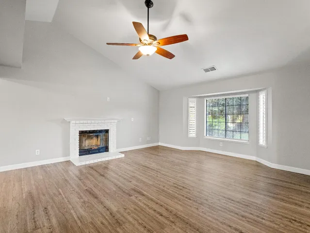 a view of an empty room with window and wooden floor