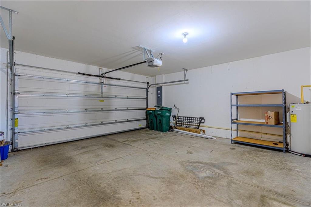 15389 Summit Pl Circle, Unit 286 Naples, FL 34119 - Photo 24 of 29 Garage featuring water heater, electric panel, and a garage door opener