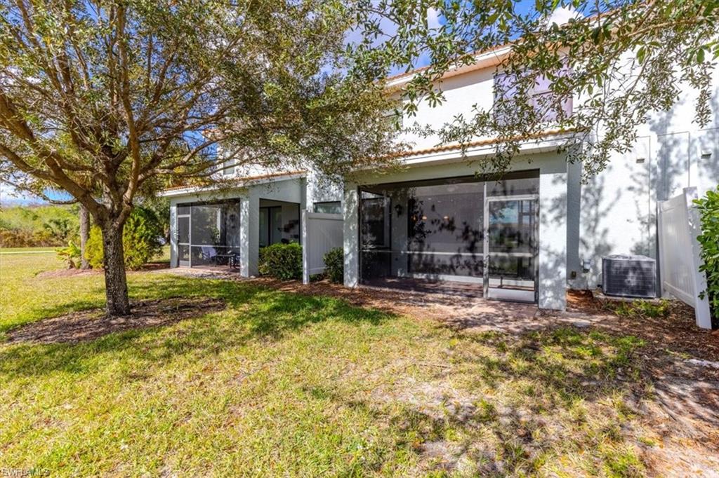 15389 Summit Pl Circle, Unit 286 Naples, FL 34119 - Photo 5 of 29 Rear view of property with stucco siding, a lawn, and a sunroom