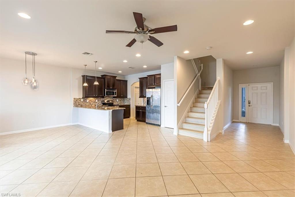 15389 Summit Pl Circle, Unit 286 Naples, FL 34119 - Photo 7 of 29 Kitchen with dark wood finish cabinets, a peninsula, stainless steel appliances, backsplash, and a ceiling fan