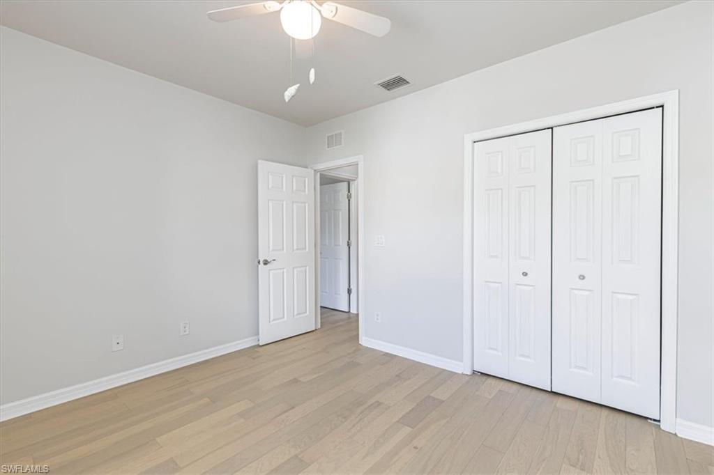 15389 Summit Pl Circle, Unit 286 Naples, FL 34119 - Photo 10 of 29 Unfurnished bedroom with a ceiling fan, light wood finished floors, and a closet