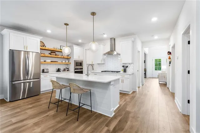 a kitchen with stainless steel appliances a refrigerator a stove a sink dishwasher and a dining table with wooden floor