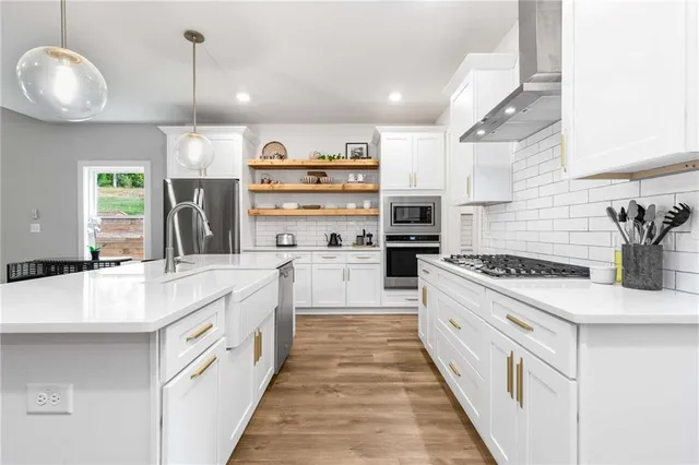 a large white kitchen with stainless steel appliances and white cabinets
