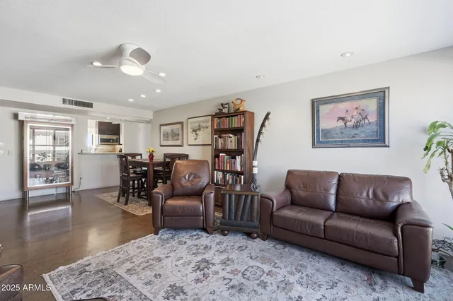 a living room with furniture kitchen view and a wooden floor