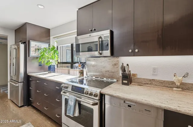 a kitchen with stainless steel appliances granite countertop a sink and a refrigerator