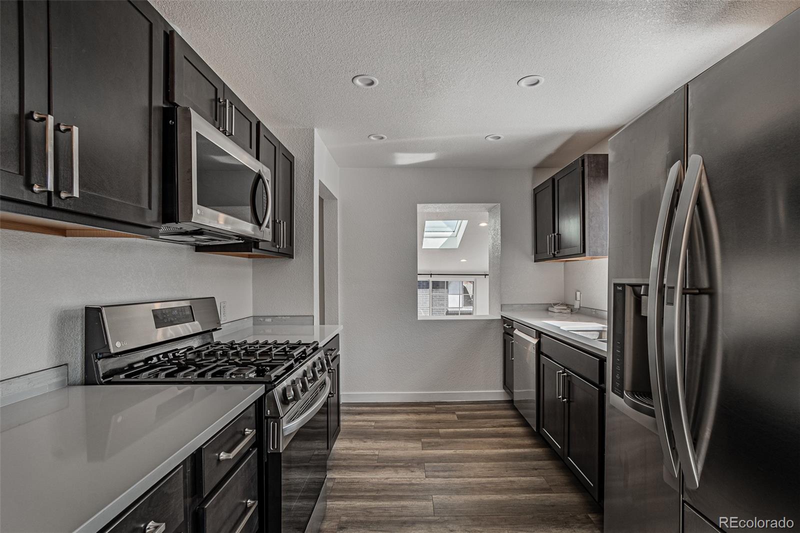3360 Magnolia Street Denver, CO 80207 - Photo 14 of 31 a kitchen with stainless steel appliances granite countertop a stove top oven a sink dishwasher a refrigerator and cabinets with wooden floor