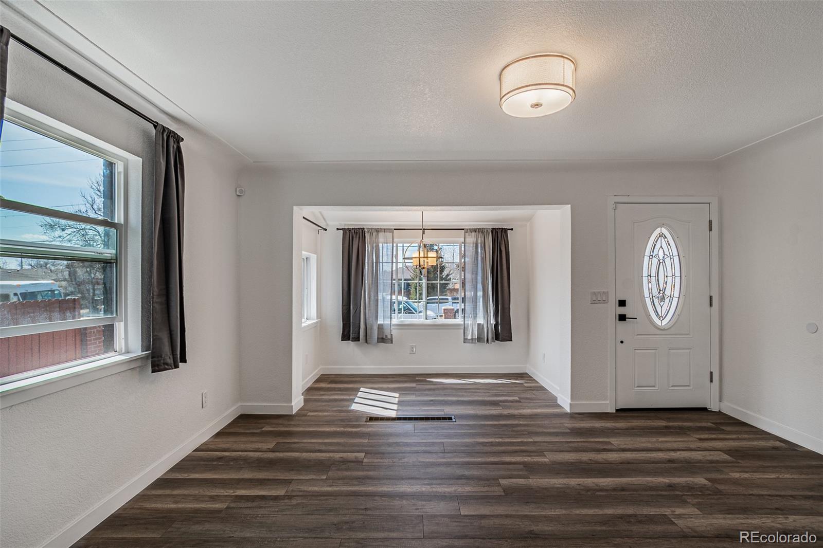 3360 Magnolia Street Denver, CO 80207 - Photo 5 of 31 a view of an empty room with wooden floor and a window