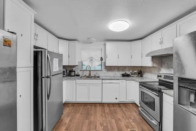 a kitchen with white cabinets stainless steel appliances and a sink