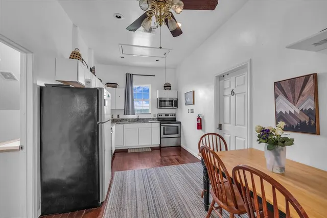 a kitchen with stainless steel appliances granite countertop a refrigerator a stove a sink dishwasher and a dining table with wooden floor