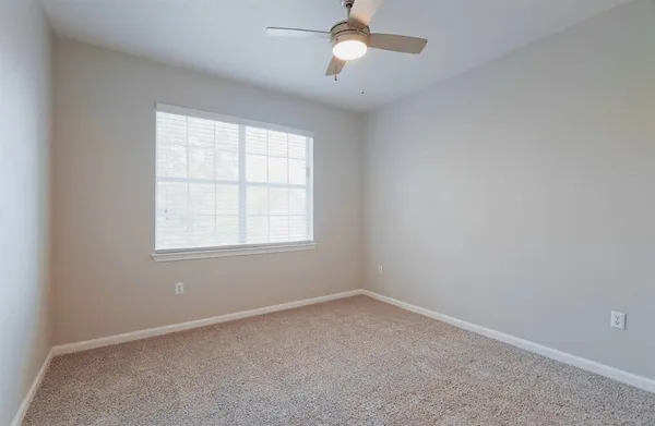 an empty room with a window and a fan