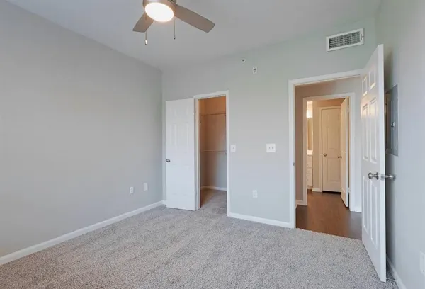 an empty room with closet and a chandelier fan