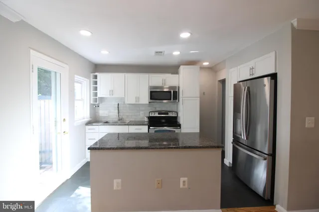 a kitchen with stainless steel appliances granite countertop a refrigerator and a stove