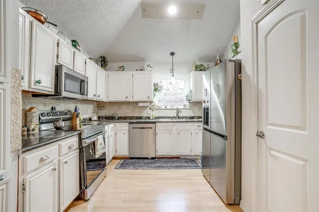 a kitchen with stainless steel appliances granite countertop a refrigerator sink and white cabinets