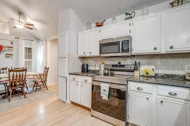 a kitchen with cabinets appliances and a dining table