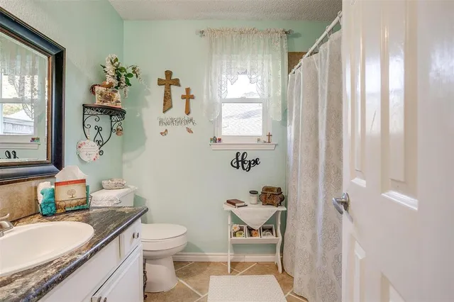 a bathroom with a granite countertop sink toilet and a mirror