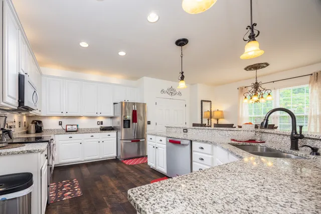 a large kitchen with stainless steel appliances kitchen island granite countertop a stove a sink a dining table and chairs with wooden floor