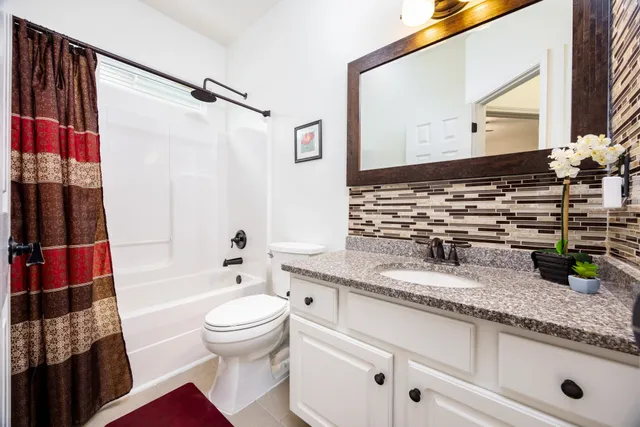 a bathroom with a granite countertop sink mirror vanity and toilet