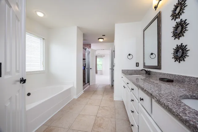 a spacious bathroom with a granite countertop tub sink and mirror