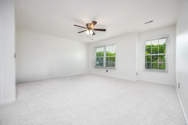 an empty room with windows and chandelier fan