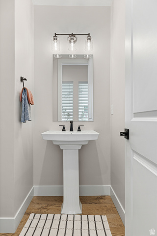 839 Walker Way St. George, UT 84770 - Photo 18 of 32 Pedestal sink with matte black faucet, wall-mounted mirror, and three-light vanity fixture with clear glass shades