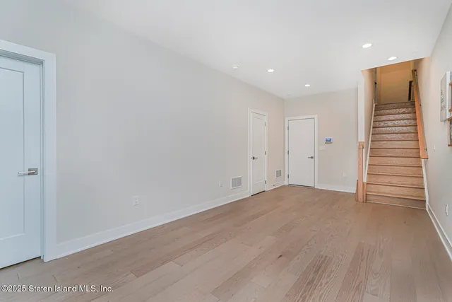 a view of staircase with wooden floor and white walls