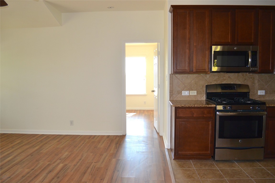 9201 Brodie Lane, Unit 101 Austin, TX 78748 - Photo 11 of 24 a kitchen with stainless steel appliances granite countertop a stove a microwave and a refrigerator